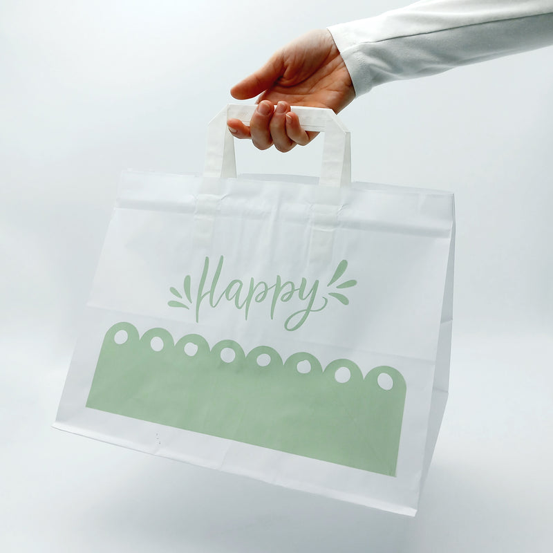 Shopper bianca, a fondo largo, con grafica verde happy, retta da una mano