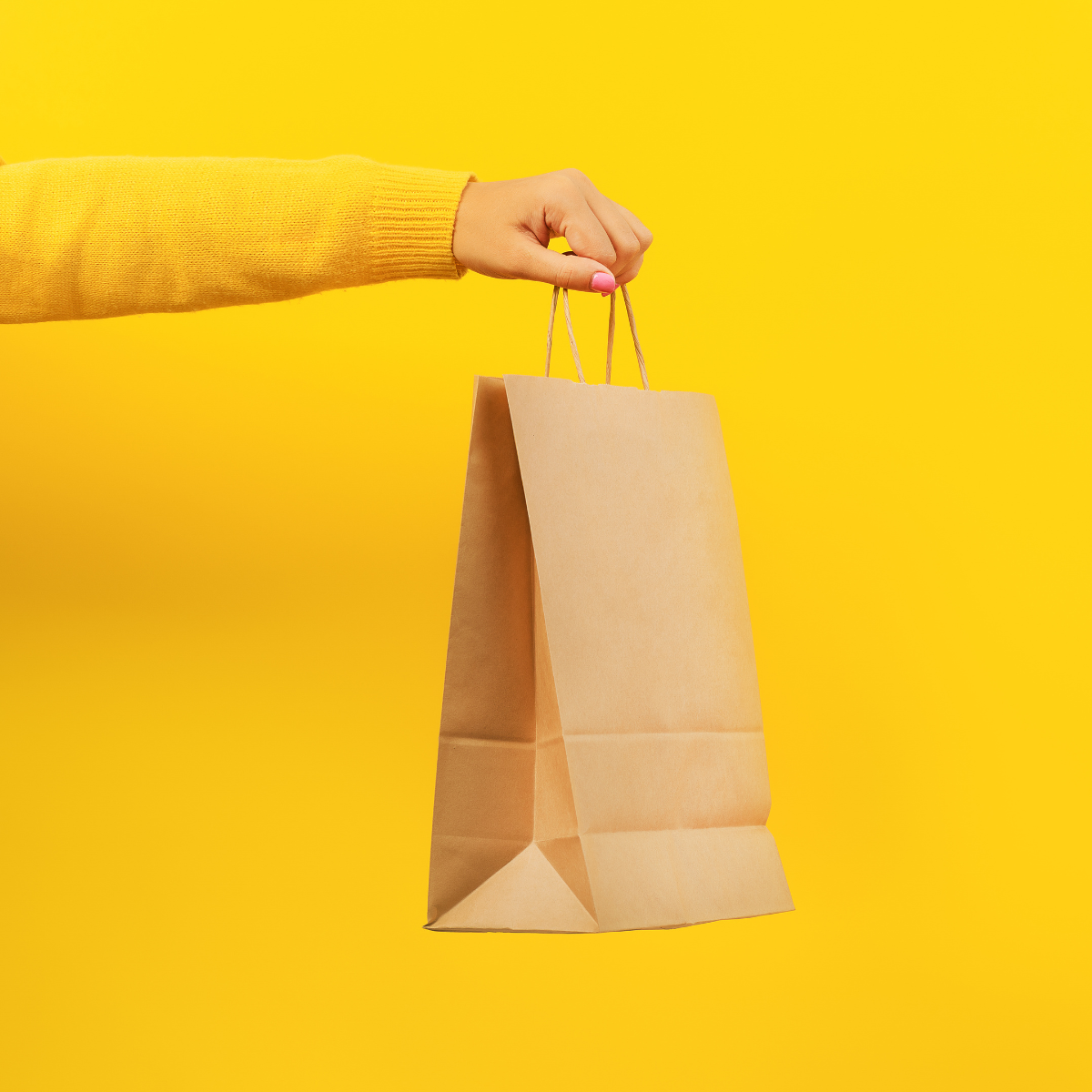 Mano che regge una shopper  di carta color avana 
