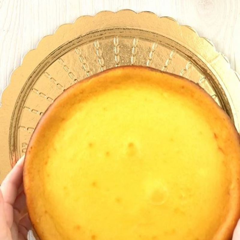 Sotto torta tondo dorato e mani che ci posano sopra una torta 