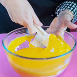 Ciotola con crema dentro e mani che la girano con una spatola