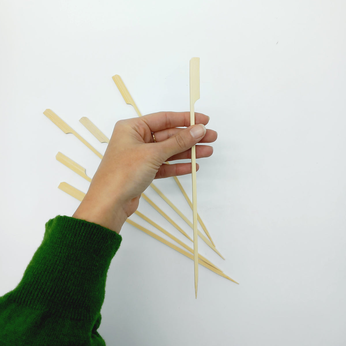 Vari spiedi di bamboo stesi ed uno tenuto da una mano