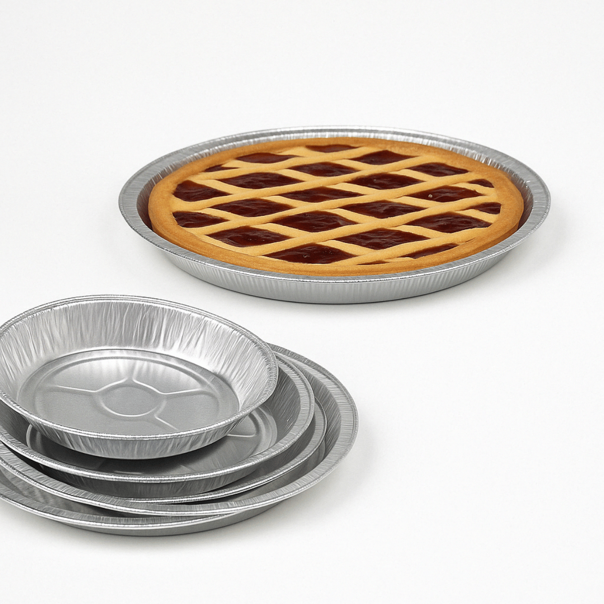 Stampi in alluminio di diverse dimensioni. Uno riempito con una crostata, altri 5 impilati vuoti