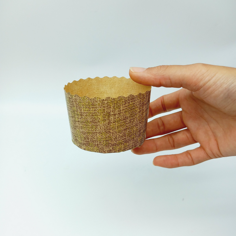 Stampo di carta per mini panettone retto da una mano 