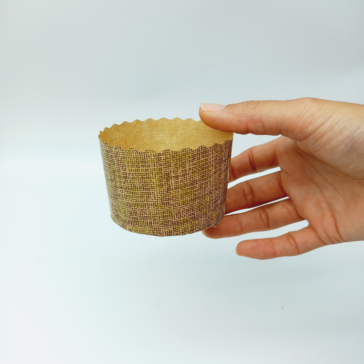 Stampo di carta per mini panettone retto da una mano 