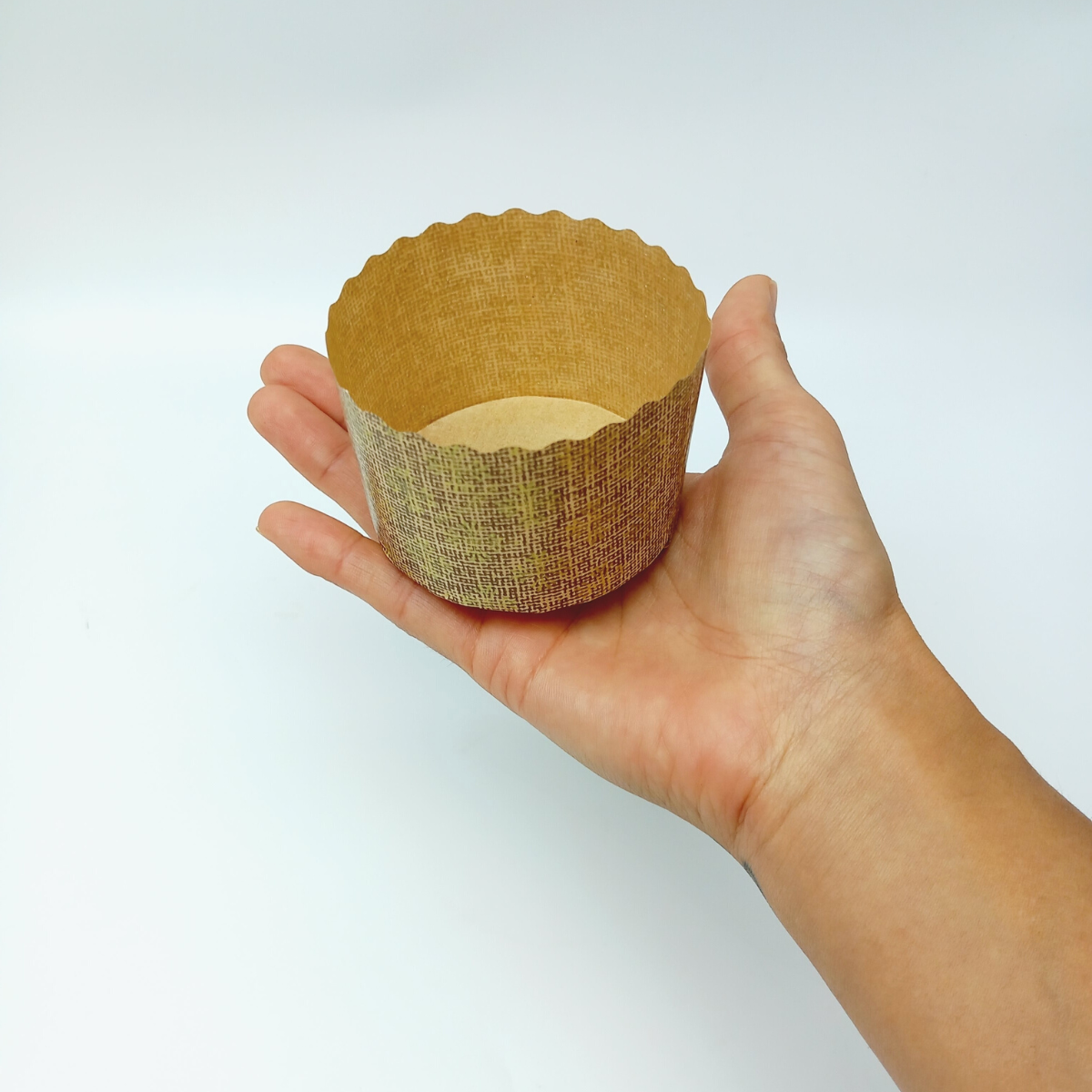 Stampo di carta per mini panettone retto da una mano 