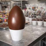 Uovo di Pasqua di cioccolato su base di plastica bianca in un laboratorio pasticceria 
