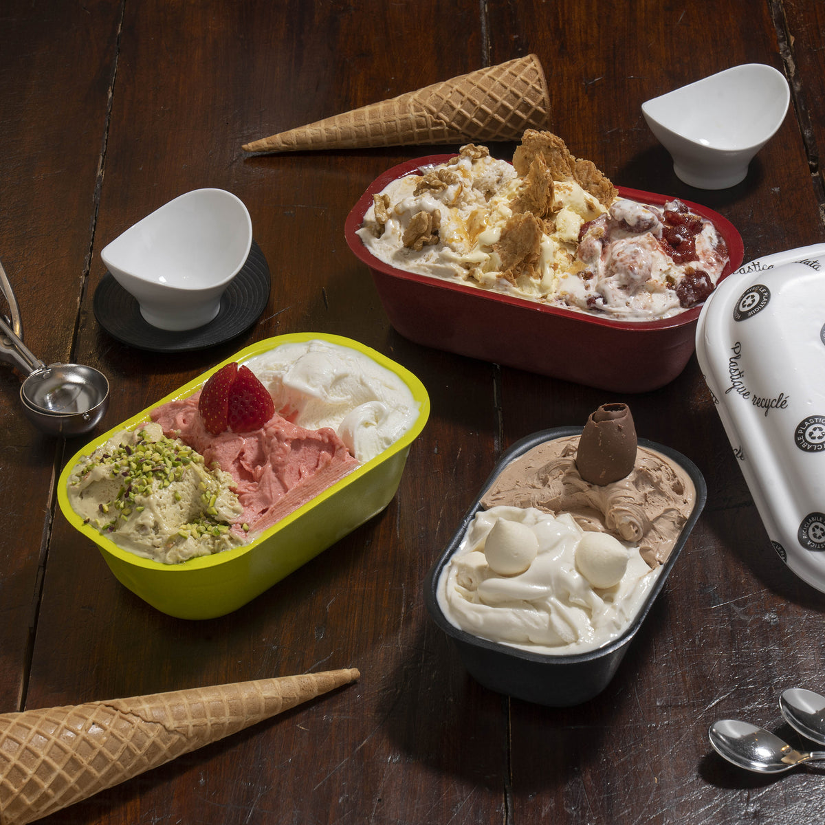 Vaschette di gelato colorate, piene di gelato, su un tavolo di legno