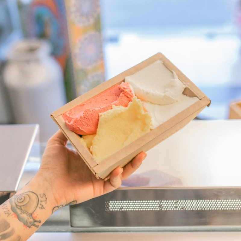 Mano che regge vaschetta di cartone piena di gelato