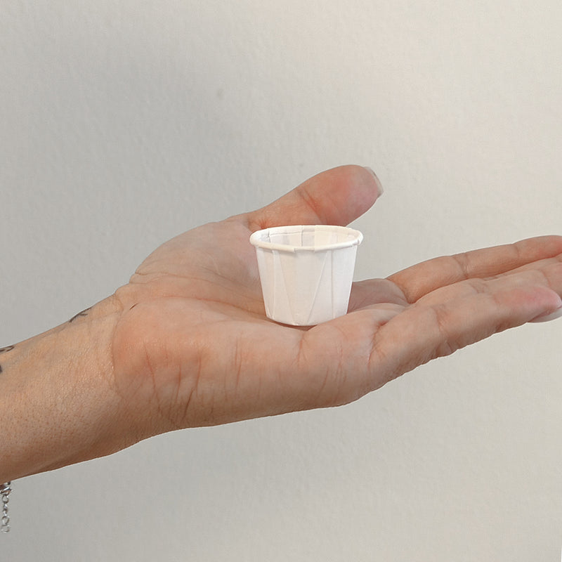Mano che tiene vaschetta color bianco per salse 