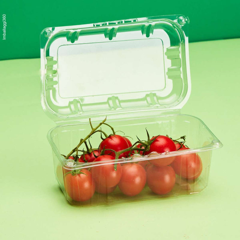Vaschetta trasparente per frutta e verdura, ripiena di pomodorini, su sfondo verde