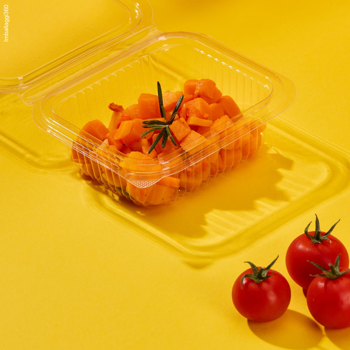Vaschette trasparenti per gastronomia, mostrate aperta e piene di cibo . Pomodorini sparsi tutto su sfondo giallo
