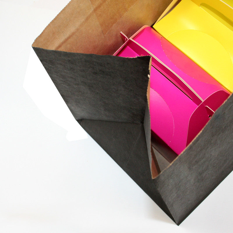 Dettaglio su busta di carta nera che contiene confezioni colorate 