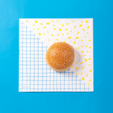 Tovagliolo di carta meta scacchi  con linee blu e meta con grafica gialla ed un panino sopra