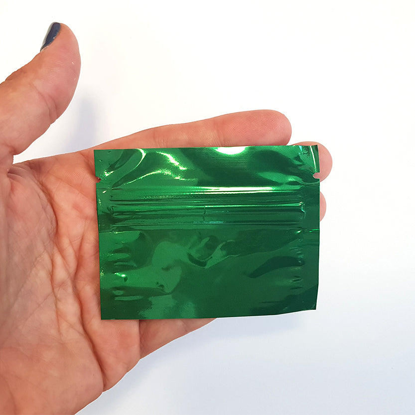 Busta di plastica con zip color verde tenuta da una mano 