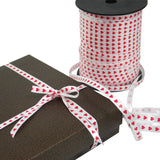 Scatola scura confezionata con nastro bianco con cuoricini rossi 