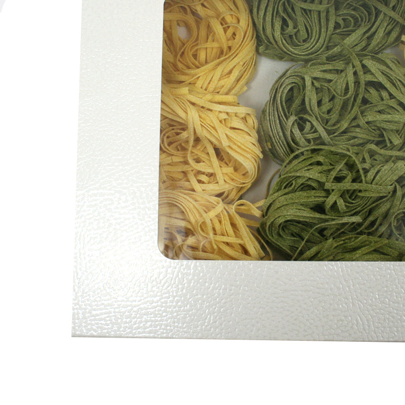 Dettaglio di scatola bianca con finestra e dentro tagliatelle 