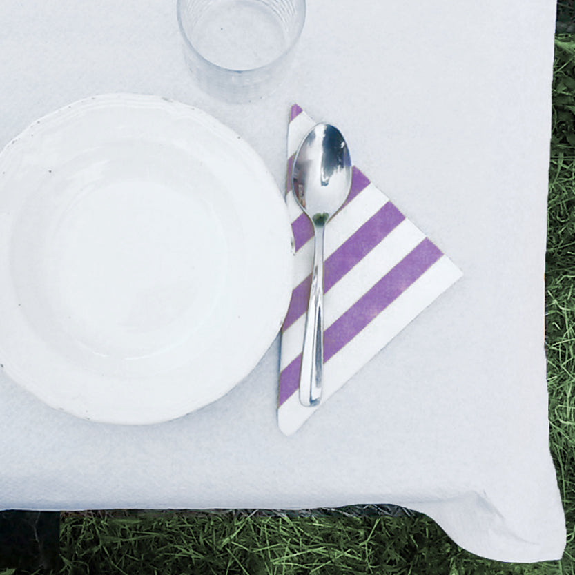 Dettaglio di tavola apparecchiata con piatto, tovagliolo di carta a righe viola