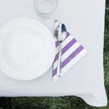 Dettaglio di tavola apparecchiata con piatto, tovagliolo di carta a righe viola