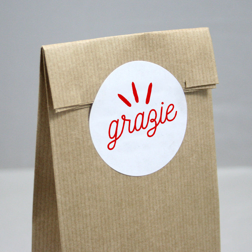 Etichetta bianca tonda adesiva con scritto grazie su sacchetto carta color avana