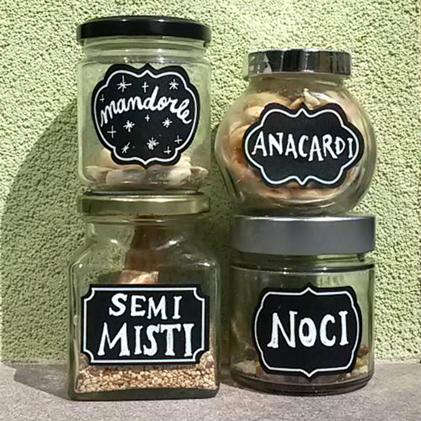 Vasetti di vetro con etichette nere con varie scritte 