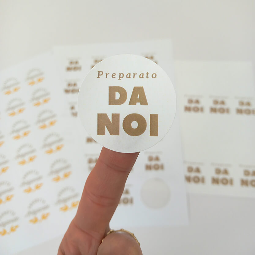 Etichetta tonda preparato da noi in primo piano su un dito e sotto sfocati i loro fogli 
