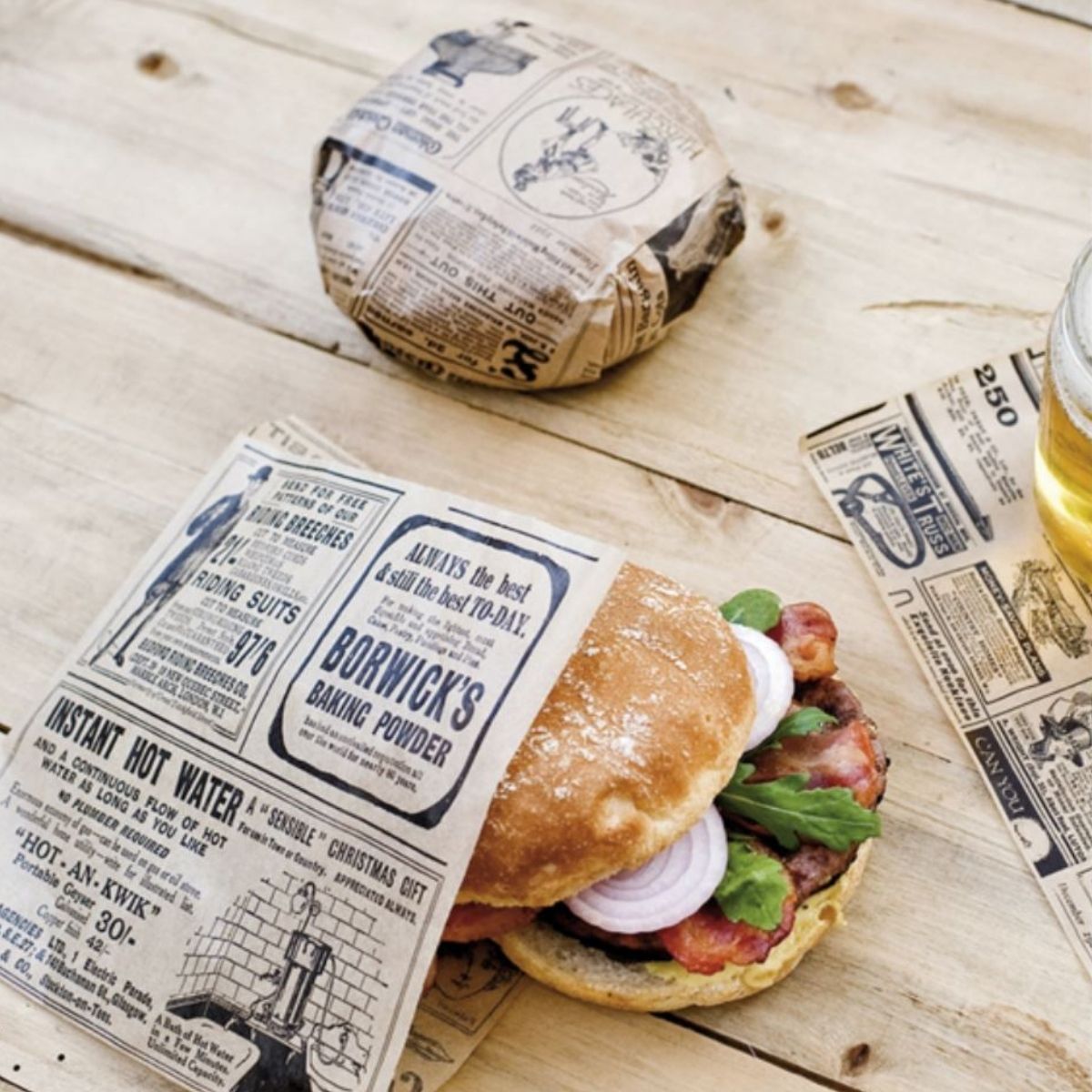 Panini avvolti da carta alimentare antigrasso avana con fantasia giornale su un tavolo di legno 