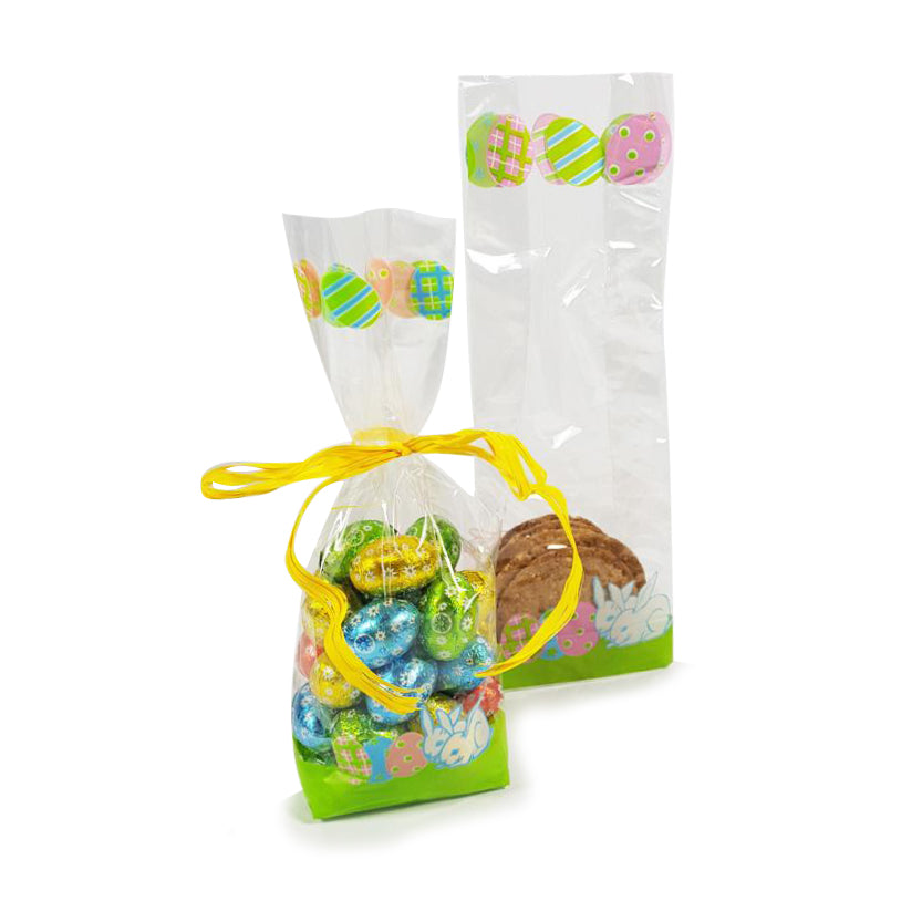 Sacchettino di plastica trasparente con fantasia primaverile pieno di ovetti di cioccolato chiuso da nastro giallo, ed uno aperto con dei biscotti dentro