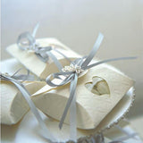 Foto di bomboniere quadrate con finestra a cuore, piene di confetti e chiuse con nastrino azzurro