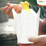 Uomo che mangia noodle da un contenitore da asporto bianco con bacchette 