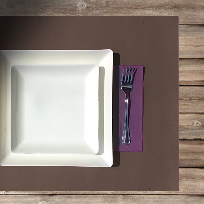 Apparecchiatura con tovaglietta americana marrone, tovagliolo di carta viola e due piatti in polpa di cellulosa quadrati uno sopra l'altro 