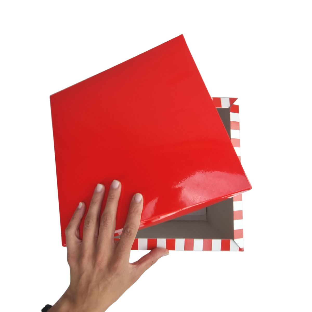Mano che apre scatola con coperchio rosso e base a righe bianchi e rosse 