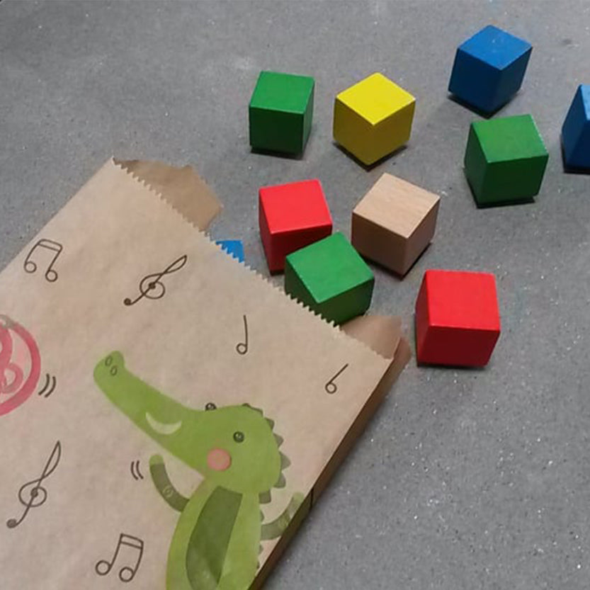 Sacchetto di carta color avana con disegno coccodrillo e cubi colorati vicino 