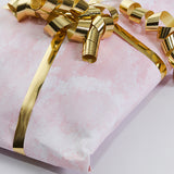 Dettaglio di vassoio incartato con carta rosa e nastro dorato 