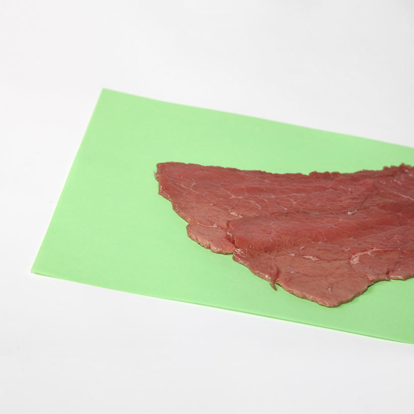 Fettina di carne su carta alimentare verde 