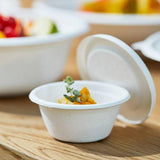 Ciotola bianca in polpa di cellulosa con coperchio su tavola con cibo dentro