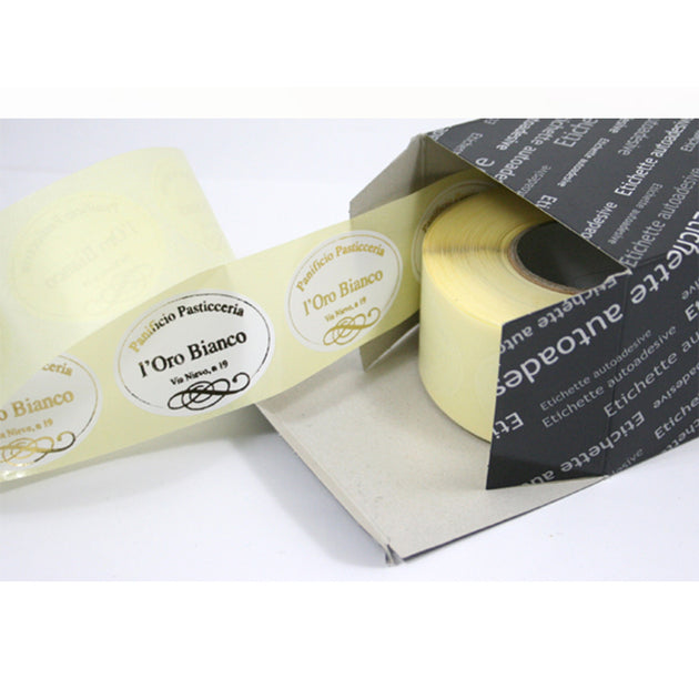 Rotolo con etichette ovali personalizzate color oro nella sua confezione mostrata aperta 
