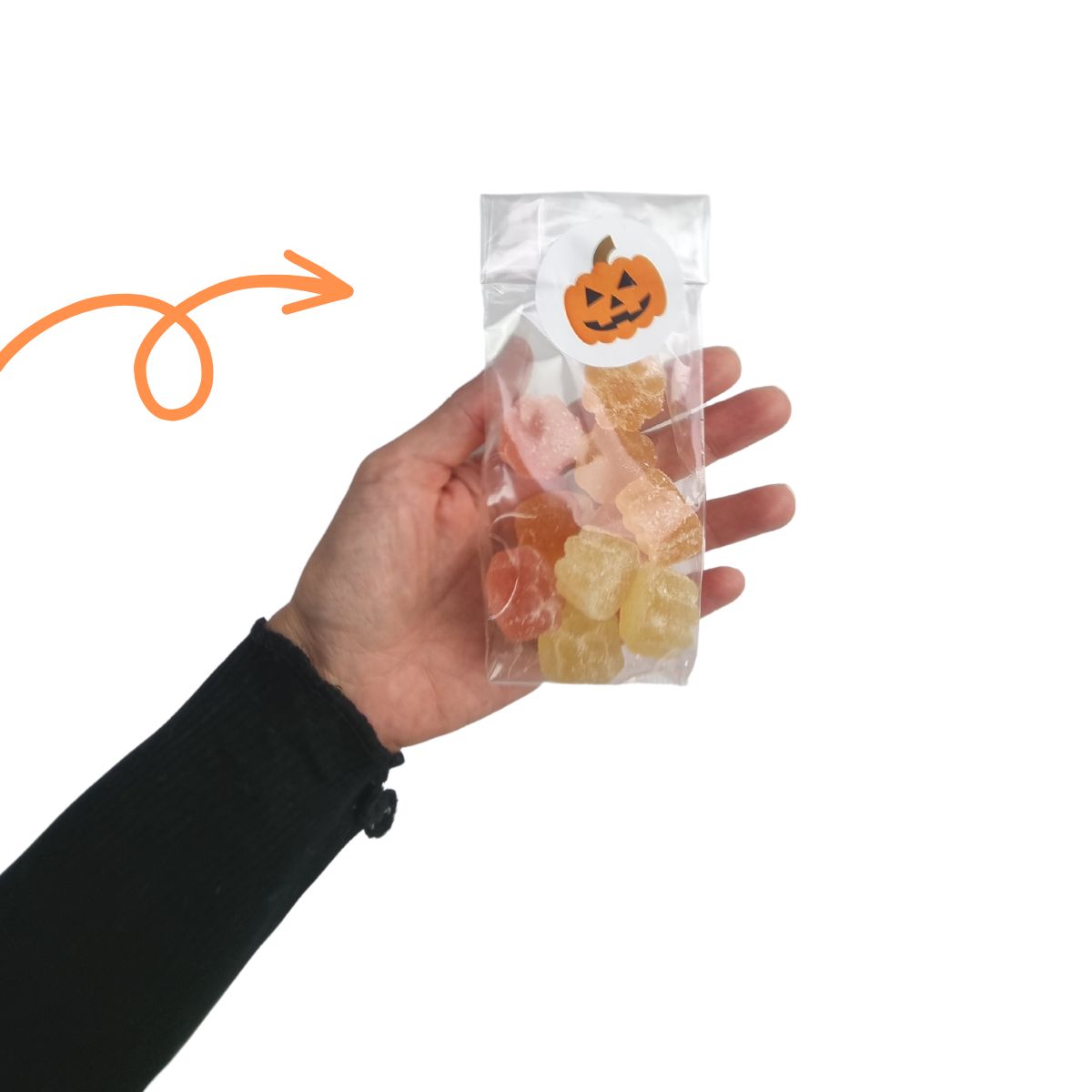 mano che regge busta di plastica trasparente con gommose chiusa da etichetta di halloween 