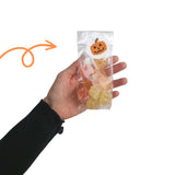 mano che regge busta di plastica trasparente con gommose chiusa da etichetta di halloween 