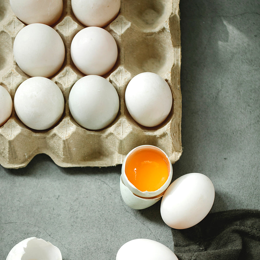 Portauova grigio con alcune uova, alcune intere ed una aperta 