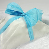 Dettaglio di pacco chiuso con carta bianca e rafia celeste 