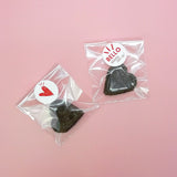 Sacchettini con dentro biscotti neri a forma di cure, due, chiusi con etichette tonde personalizzate 