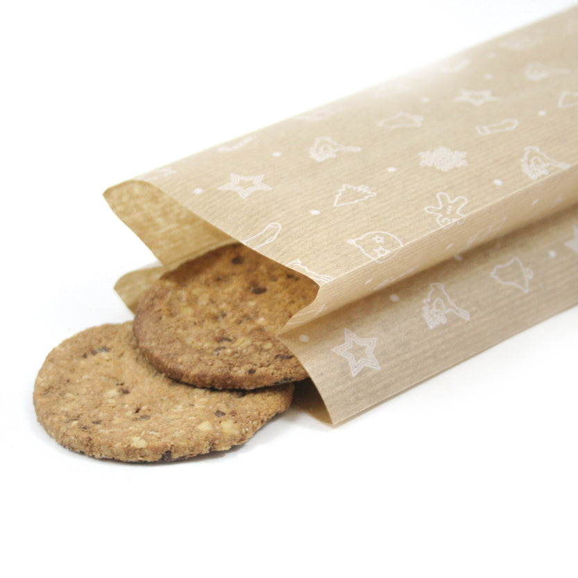 Dettaglio di sacchetto di carta avana con grafiche bianche natalizie dal quale escono due biscotti