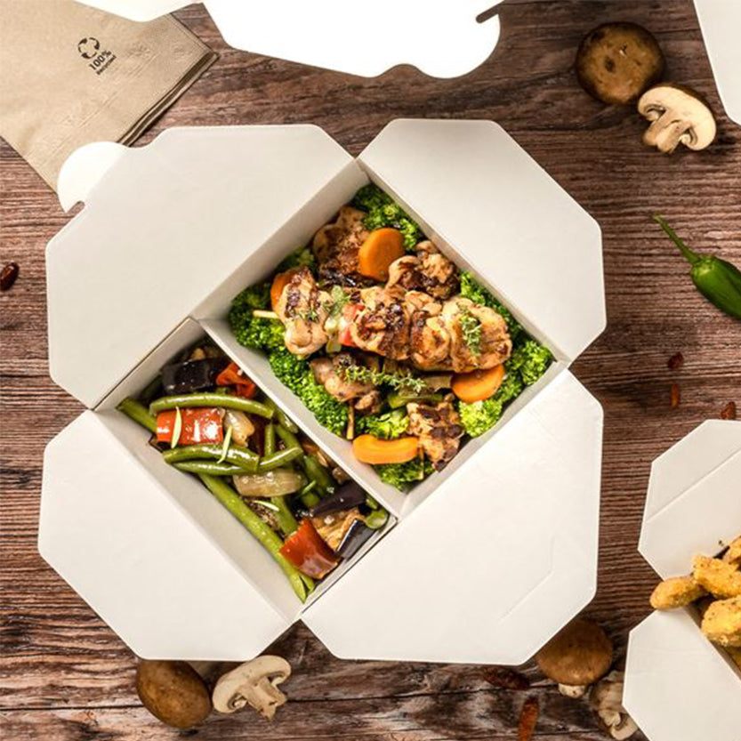 Scatola di cartone per cibo d'asporto piena di cibo vista dall'alto su tavolo 