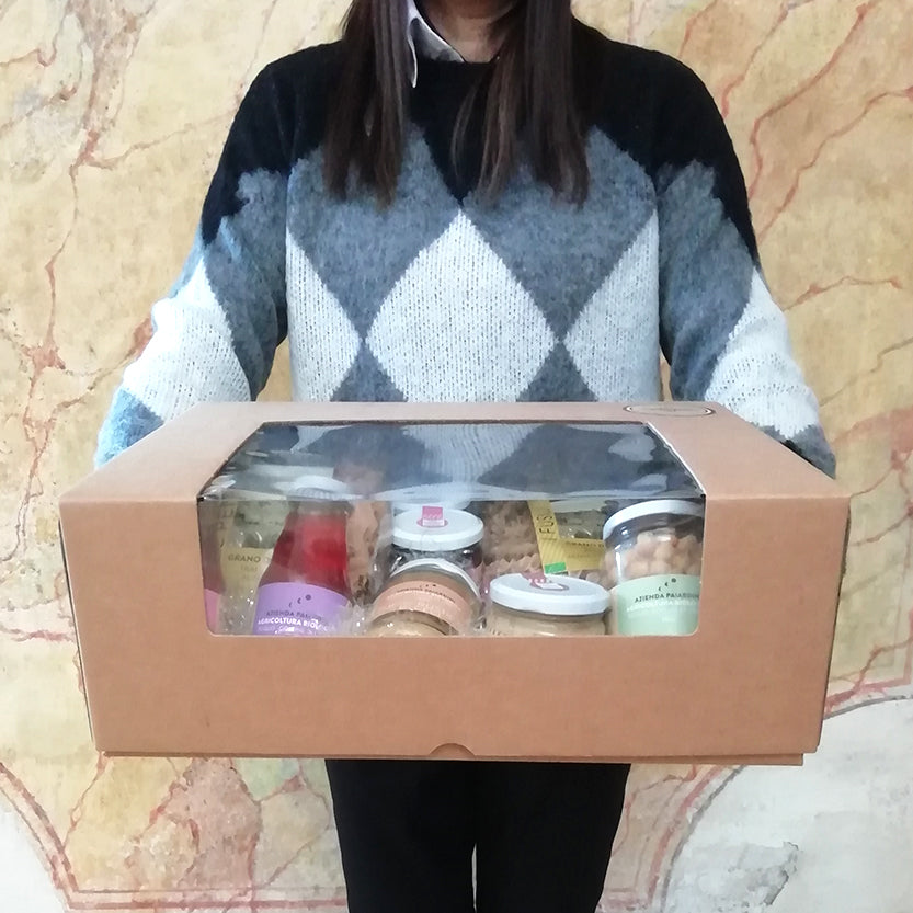 Ragazza che tiene scatola di cartone colora vana grande, con finestra piena di vasetti e prodotti