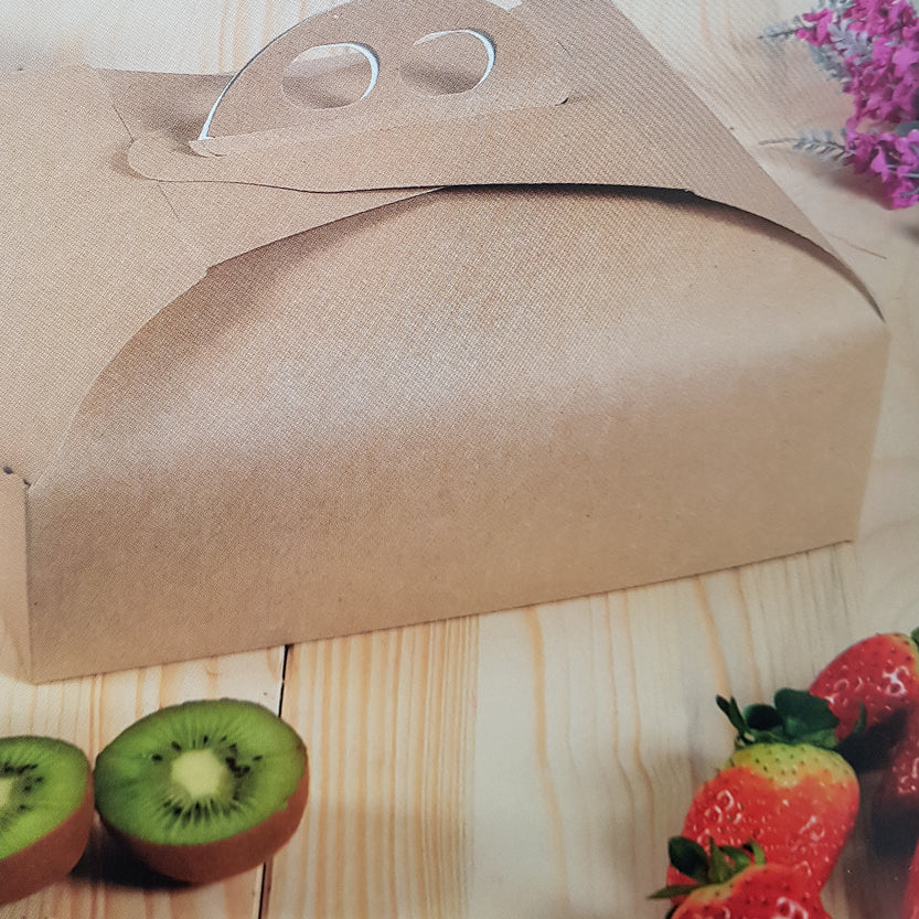Scatola porta torte avana su tavolo vicino a della frutta 