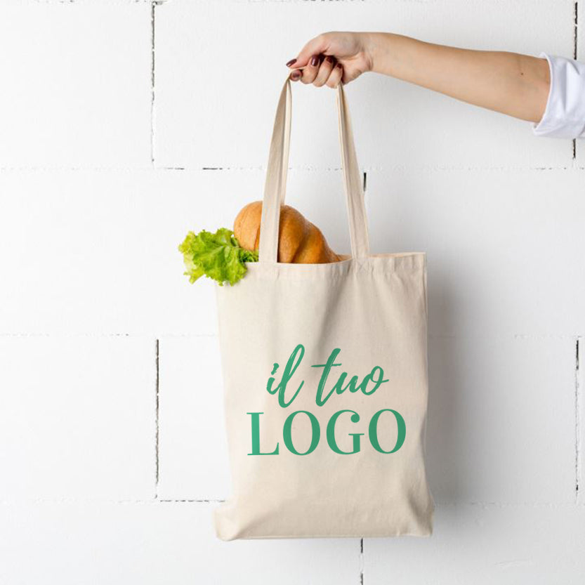 Mano che regge shopper di tela personalizzata piena di alimenti 
