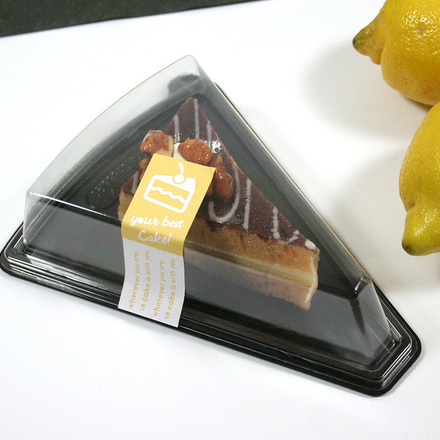 Vaschetta base nera, triangolare, per fetta di torta, con dentro una fetta di torta , sigillata da una etichetta personalizzata, su un tavolino da bar
